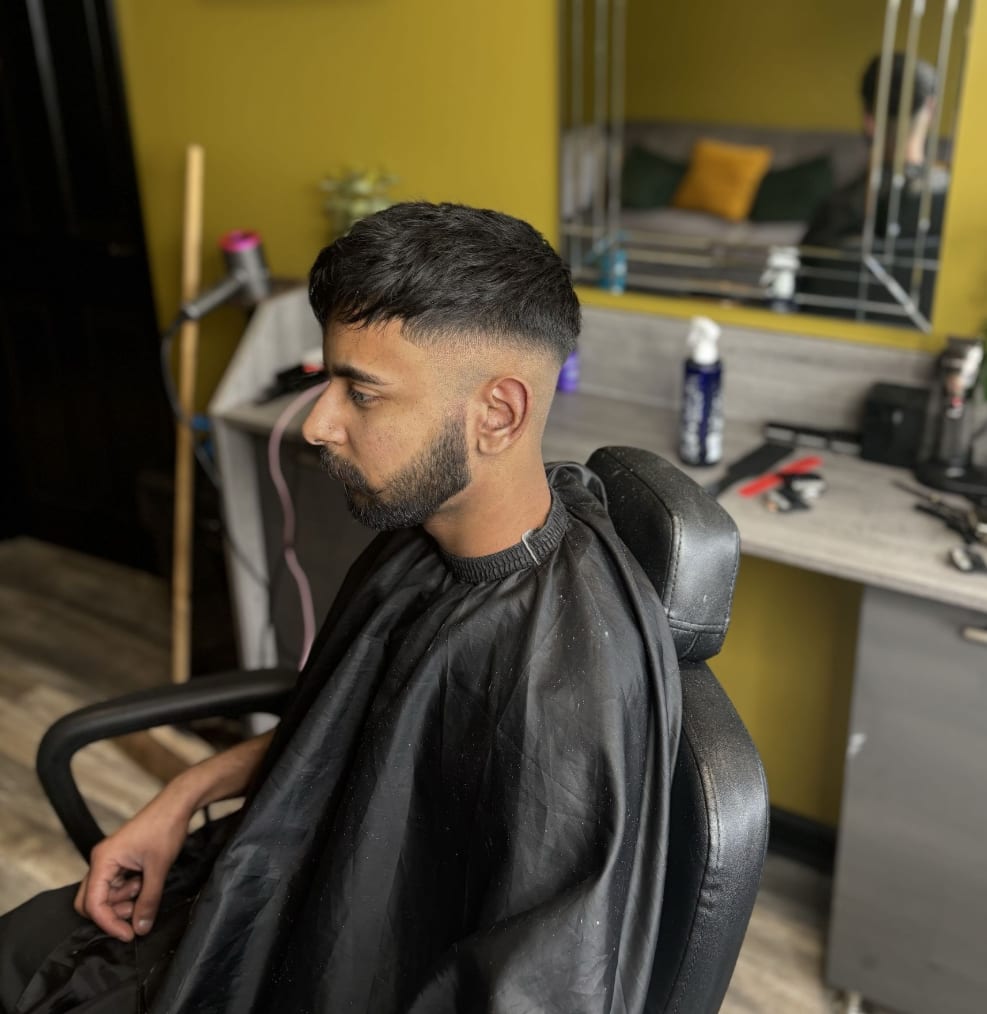 A sharp mid fade blended into a shaped beard at Kennedys