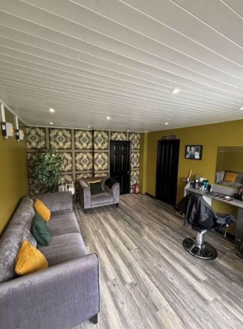 The lounge inside Kennedys with grey sofas and gold feature wallpaper